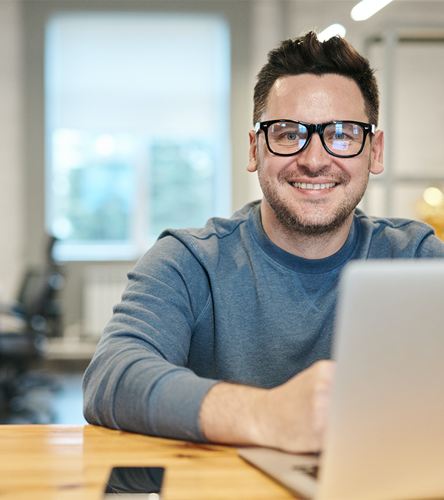 A man smiling while facing laptop